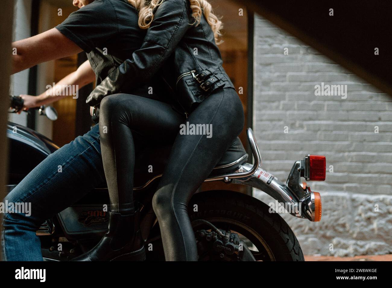 Ein Paar, das zusammen mit einem Motorrad in einer Gasse fährt Stockfoto