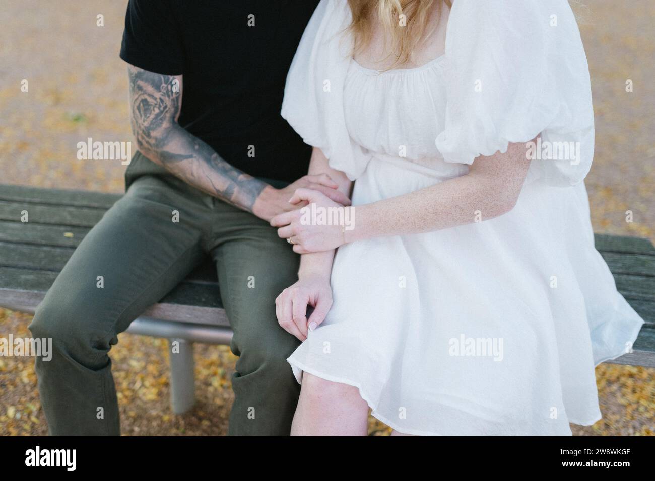 Verlobtes Paar, das Hände hält und auf einer Parkbank sitzt Stockfoto