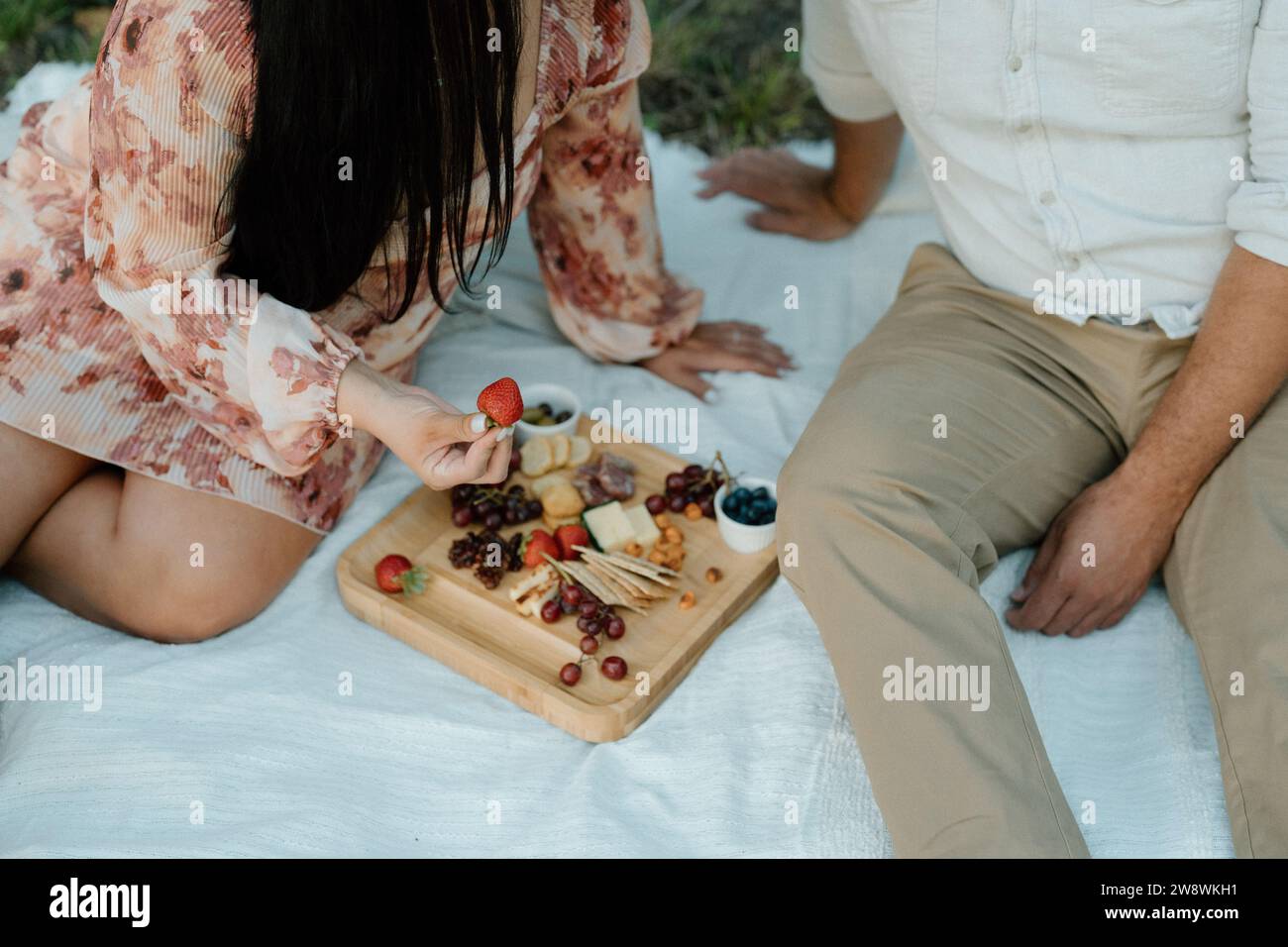 Pärchen, die bei einem Picknick mit einer Wurstplatte sitzen Stockfoto