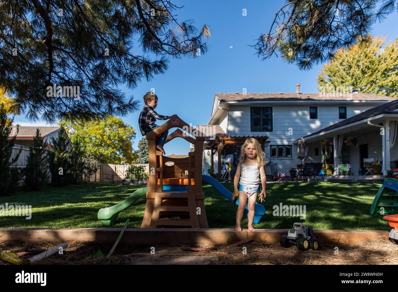 Kleinkind Mädchen in Windel spielt im Garten mit Bruder Stockfoto