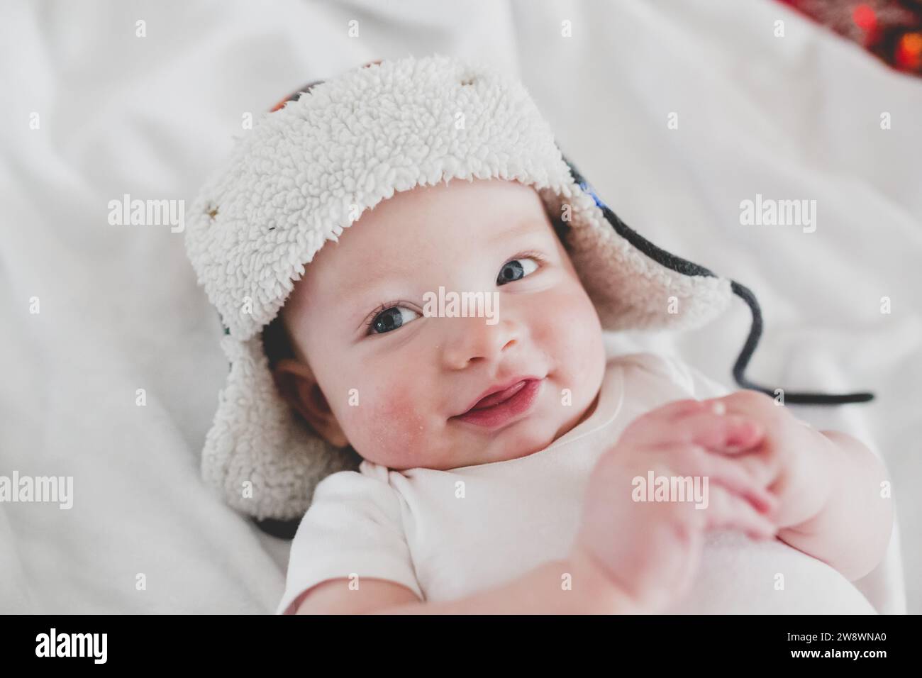 Lächelndes Baby mit Bombermütze, weiße Ästhetik Stockfoto
