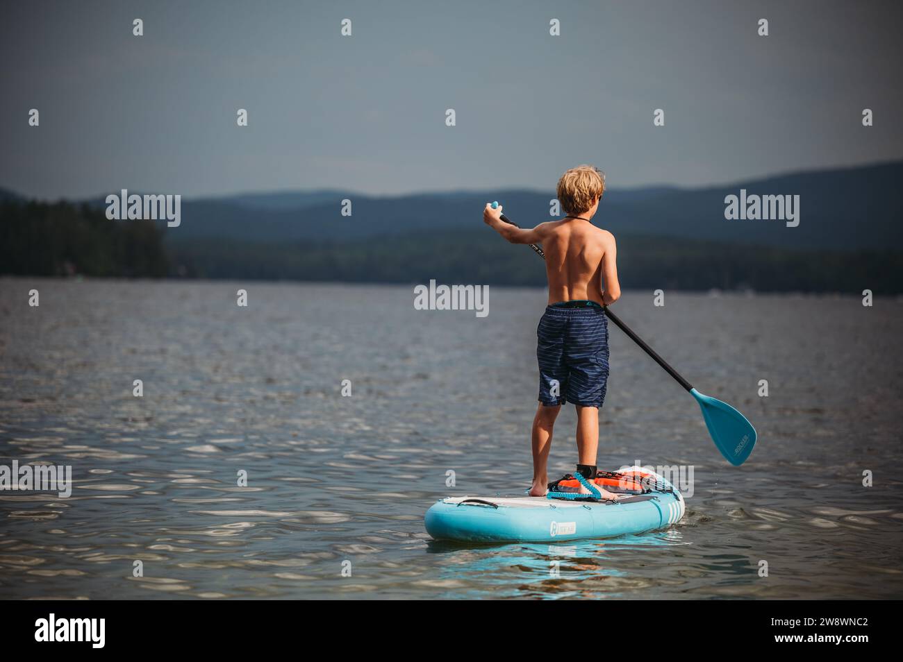 Hinter dem Tween Boy paddeln Sie auf dem See Stockfoto