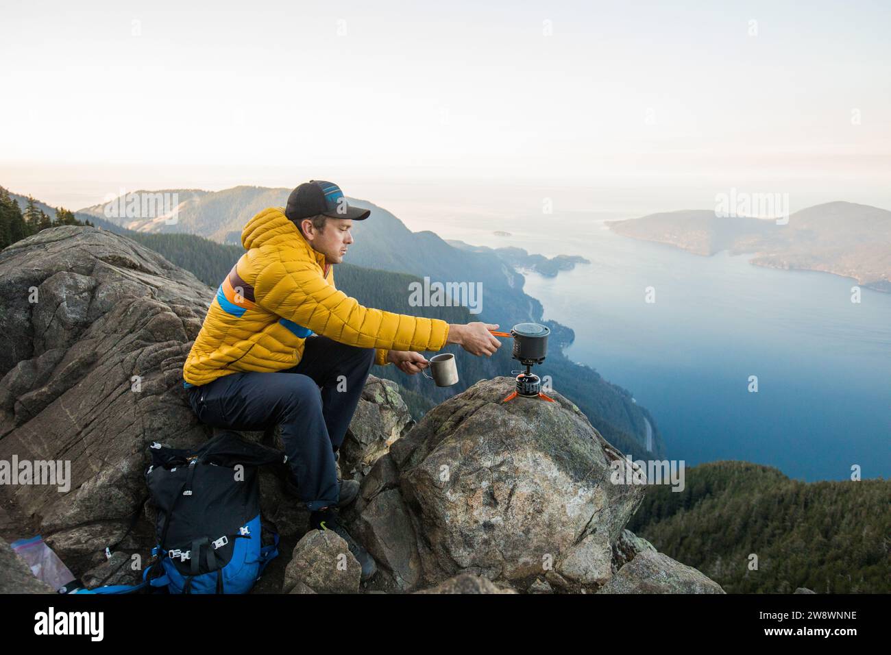 Backpacker mit Herd, um ein heißes Getränk am malerischen Aussichtspunkt zuzubereiten. Stockfoto