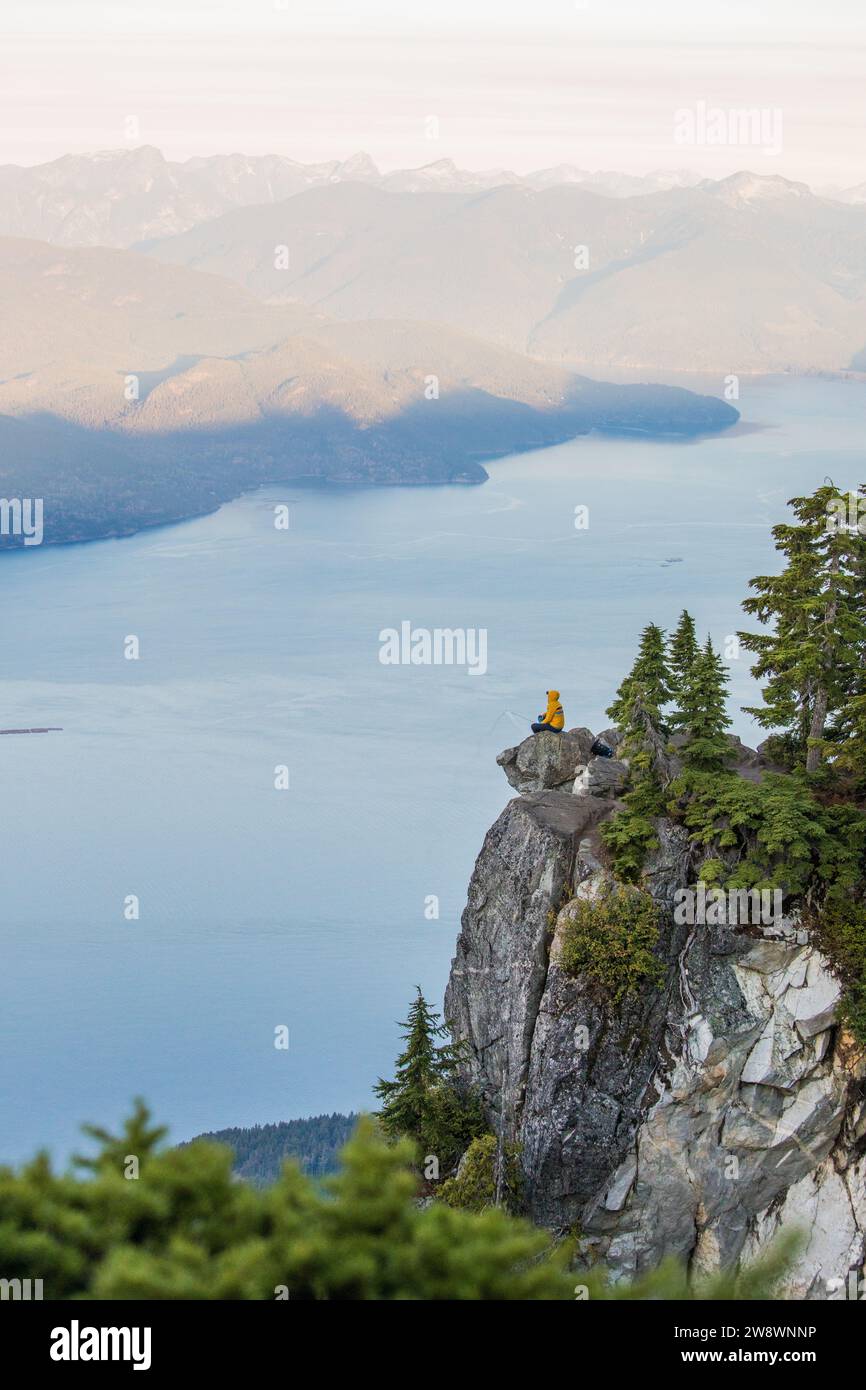 Seitenansicht eines aktiven Wanderers, der auf einer Klippe sitzt, mit atemberaubender Aussicht Stockfoto