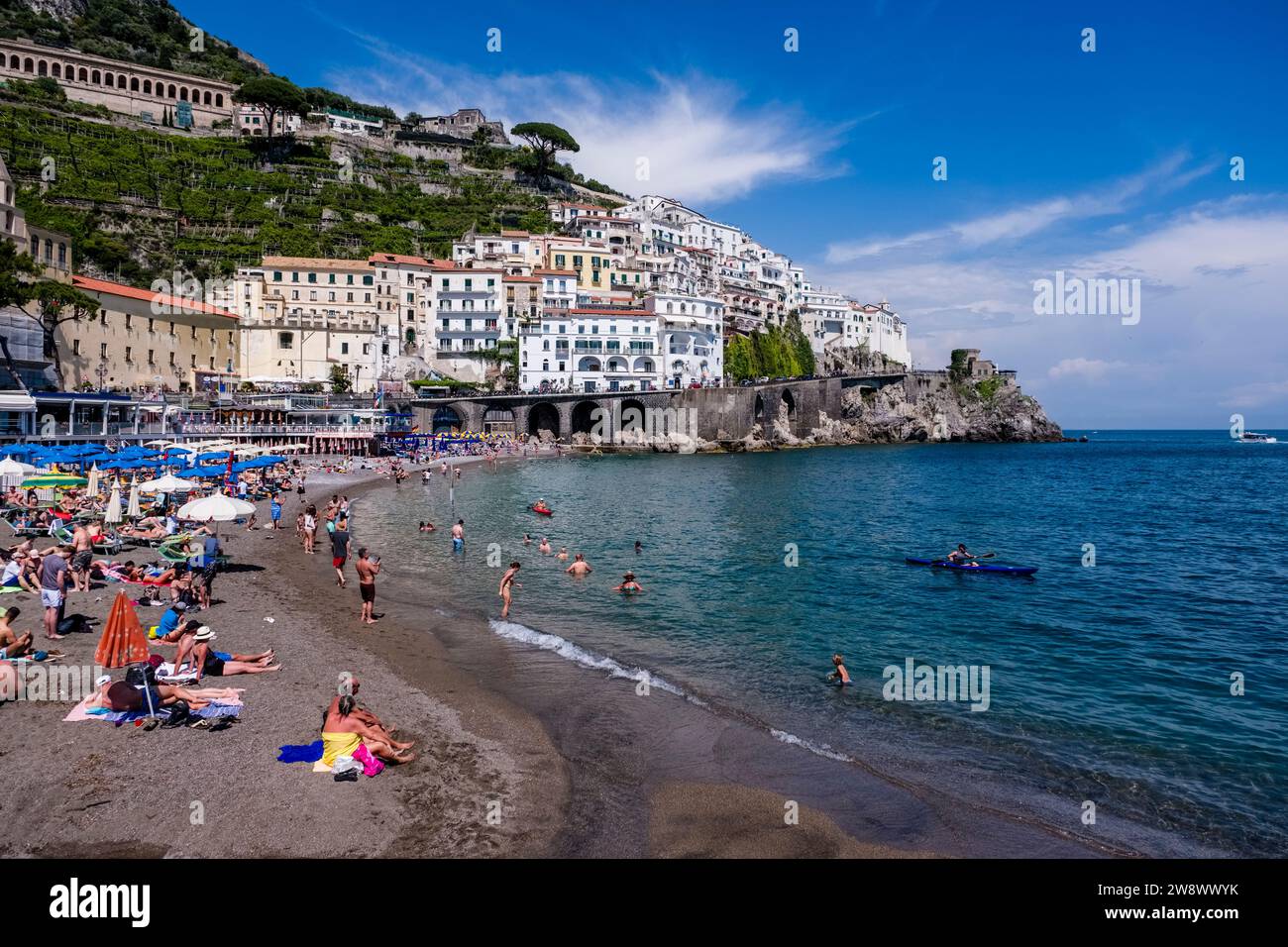 Häuser der Stadt Amalfi an der Amalfiküste, die an der Küste in einem Tal liegt, das zum Mittelmeer führt und über den Strand gesehen wird. Stockfoto