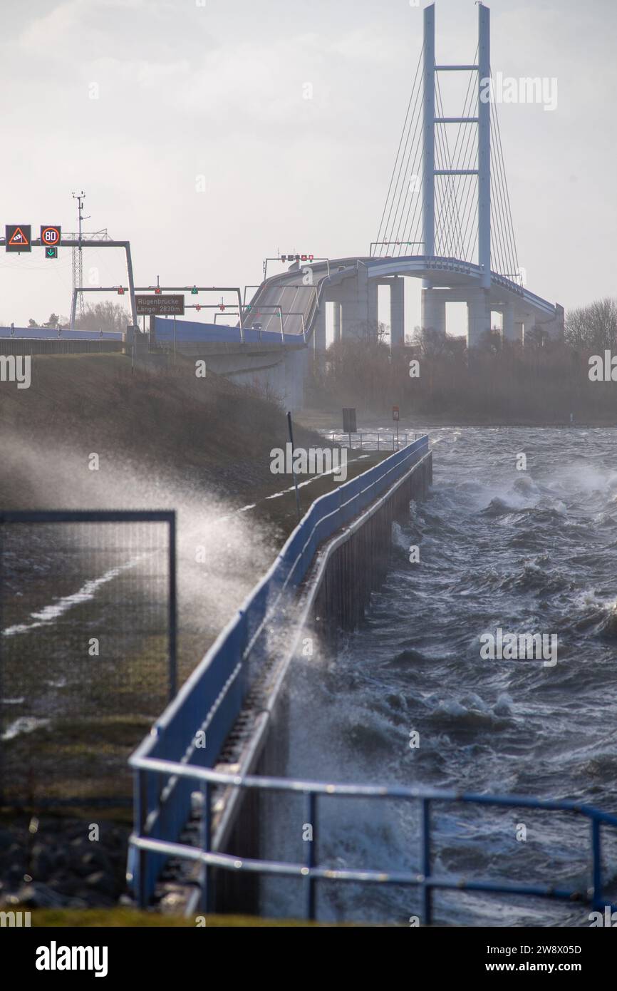 22. Dezember 2023, Mecklenburg-Vorpommern, Altefähr: Wegen des stürmischen Wetters sollten leere LKW und Wohnwagen die Rügenbrücke zwischen Stralsund und Rügen nicht überqueren. Stattdessen sollten sie über den unteren Rügendamm fahren. Elektronische Anzeigen vor der Zufahrtsstraße wiesen die Fahrer am Freitagnachmittag an, geeignete Ausweichmaßnahmen zu ergreifen. Der Deutsche Wetterdienst warnte bis Freitag vor Sturmwinden – vor allem an der Küste westlich von Rostock bis Vorpommern. Foto: Stefan sauer/dpa Stockfoto