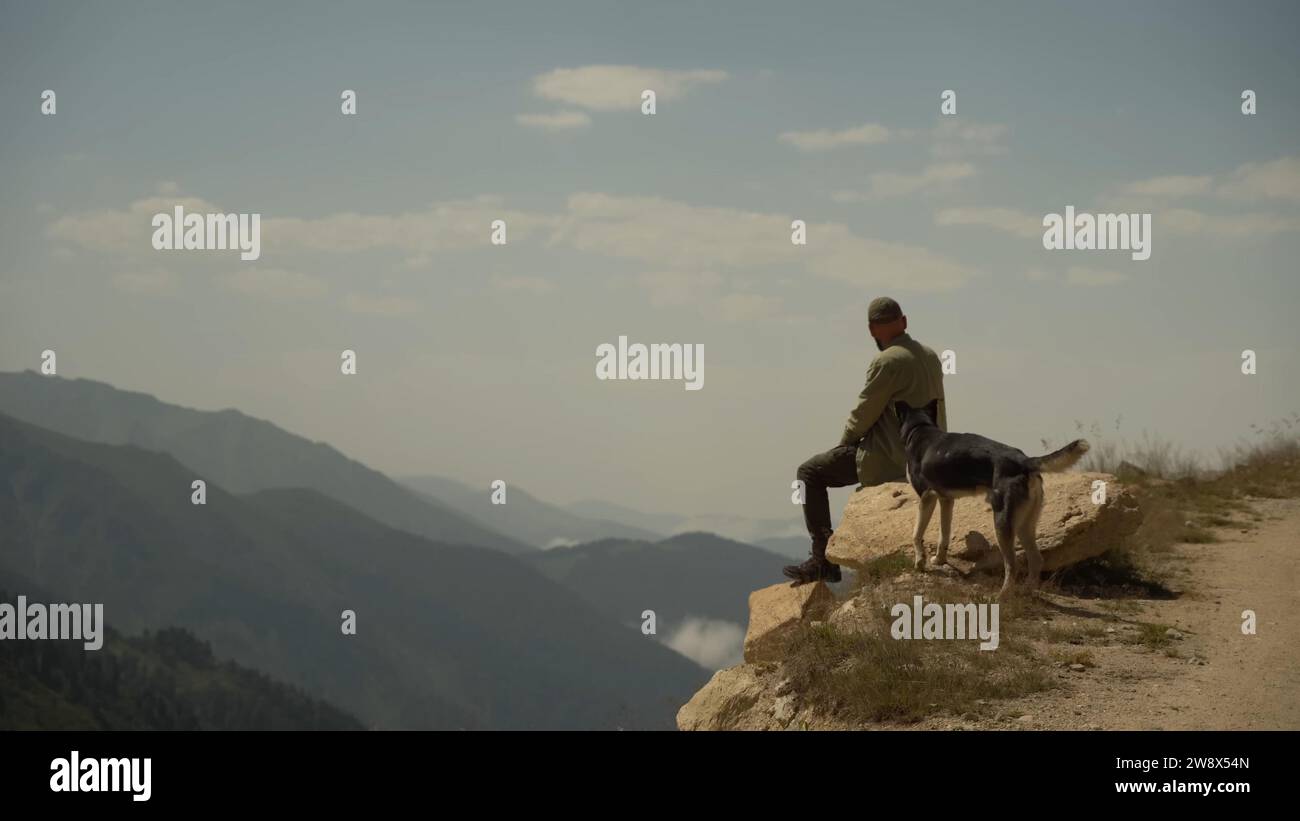 Mensch und Hund, genießen Natur, Berglandschaft, Outdoor-Abenteuer, Naturschätzen, Verbindung mit Hund, Berggipfel, friedliche Momente, Gesellschaft Stockfoto