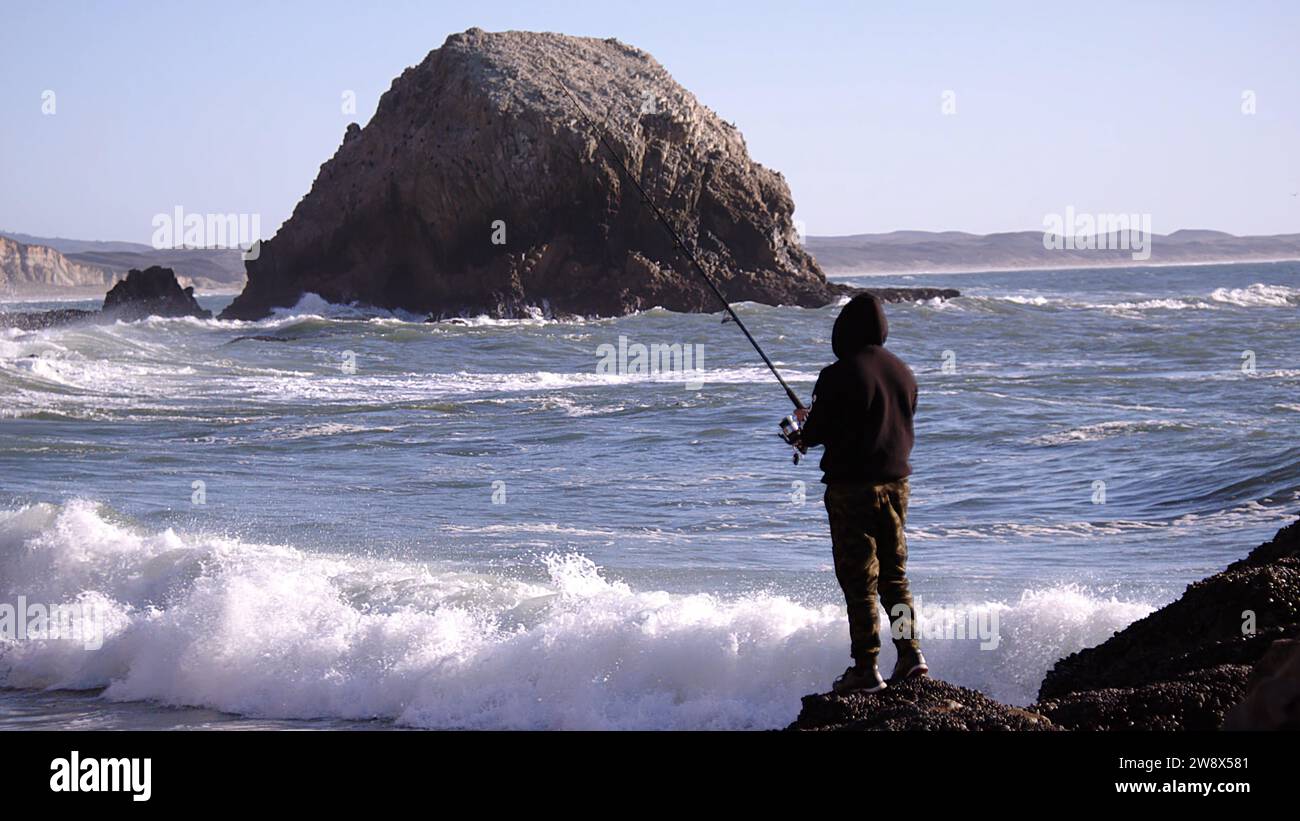 Ein Mann, der versucht, in starken Meereswellen Fische zu fangen Stockfoto