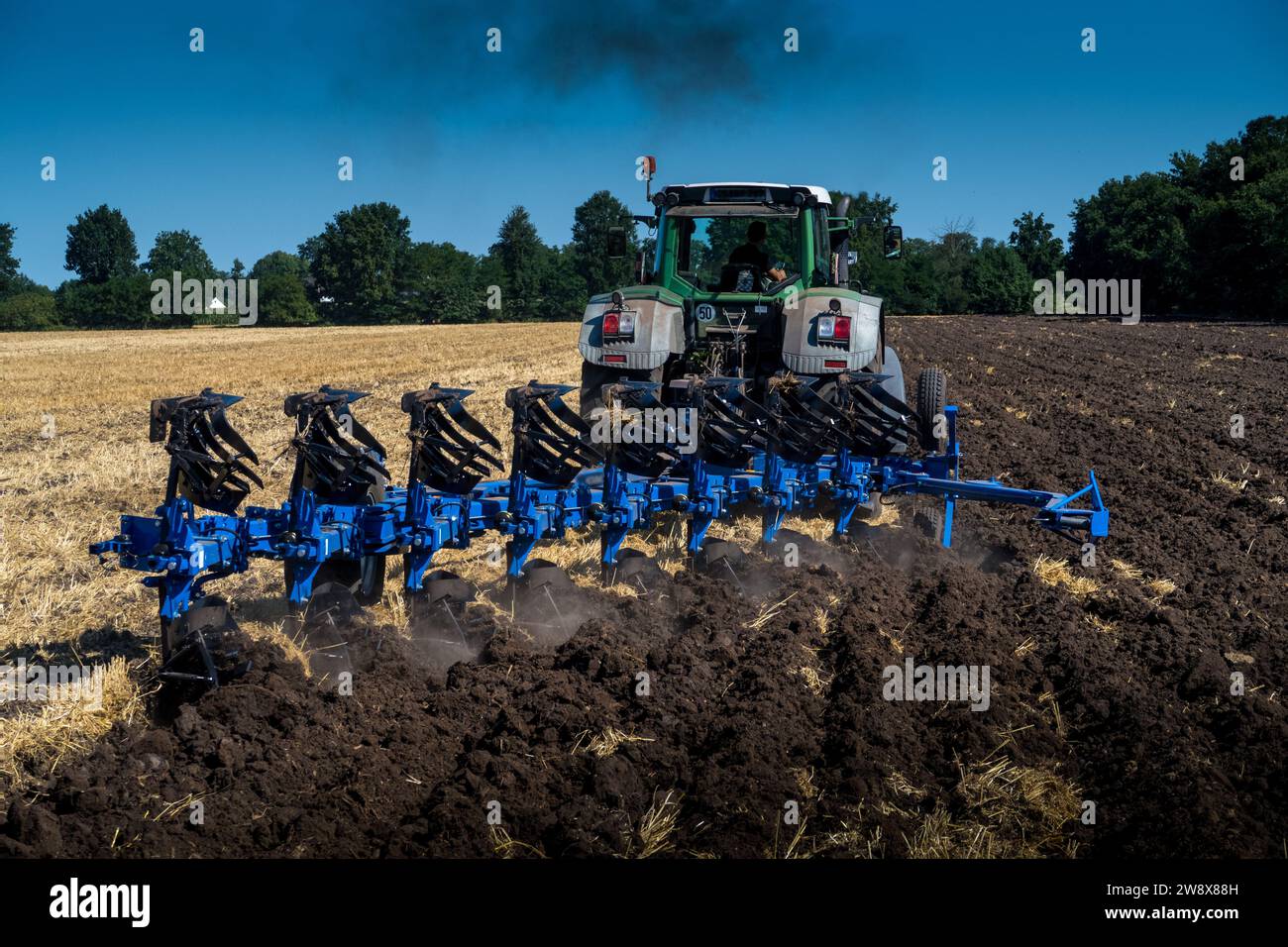 Pflügen (Wenden) eines Stoppelfeldes mit Pflug und Traktor Stockfoto