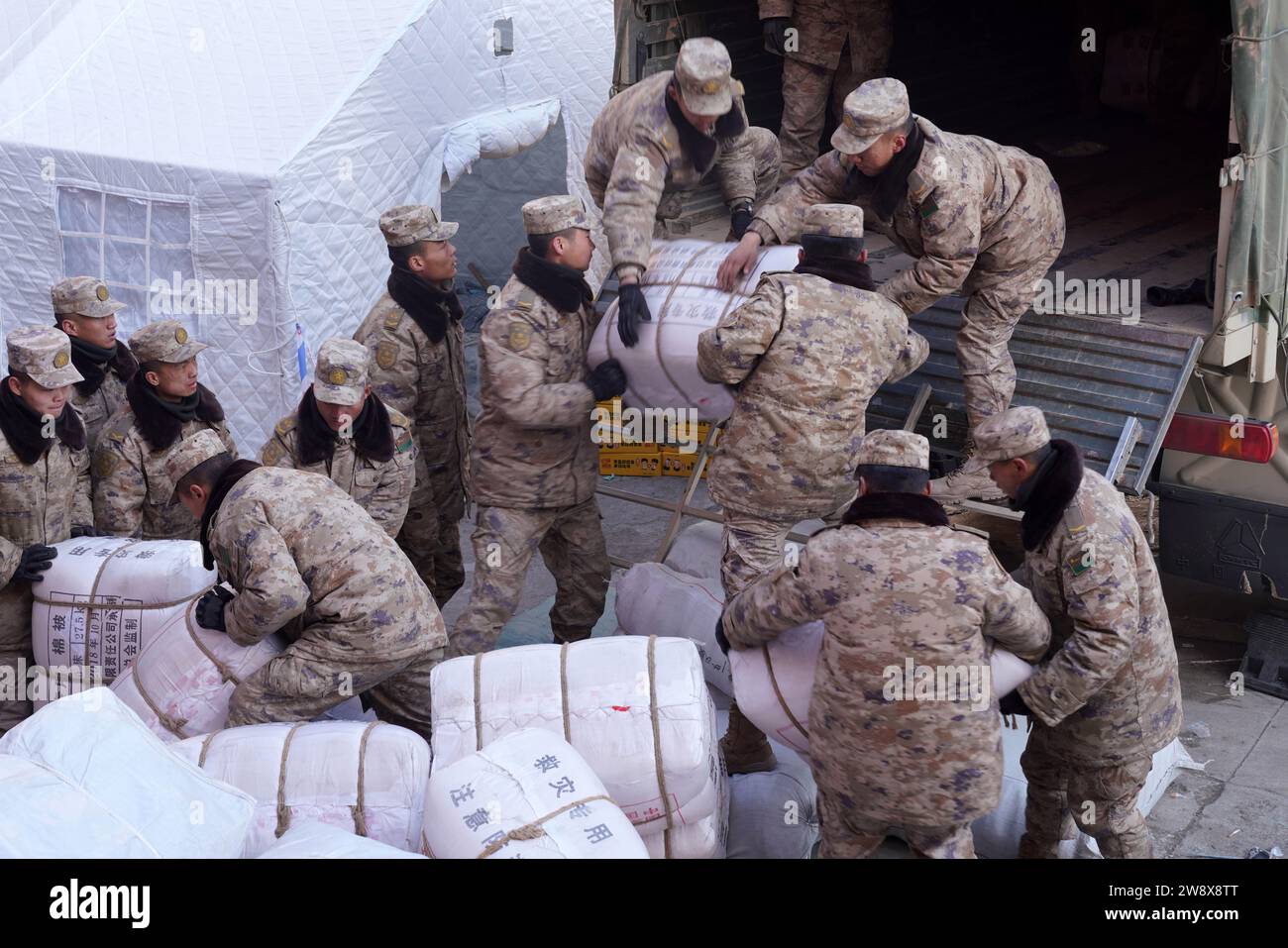 Linxia, Chinas Provinz Gansu. Dezember 2023. Soldaten transportieren Katastrophenhilfe für die von Erdbeben betroffenen Bewohner in der Gemeinde Shiyuan im Jishishan County, nordwestchinesische Provinz Gansu, 22. Dezember 2023. Die chinesische Volksbefreiungsarmee (PLA) und die Volksarmee (PAPF) haben mehrere Rettungskräfte in Gebieten eingesetzt, die von Erdbeben betroffen sind, als Reaktion auf ein Erdbeben der Stärke 6,2, das die nordwestchinesische Provinz Gansu am späten Montag erschütterte. Quelle: Zhang Yongjin/Xinhua/Alamy Live News Stockfoto