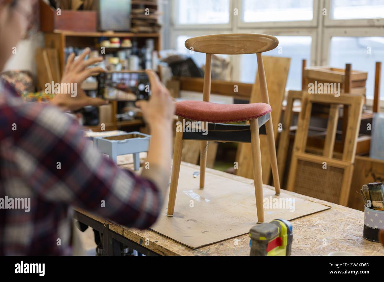 Handwerkerin macht Fotos von einem renovierten Stuhl Stockfoto