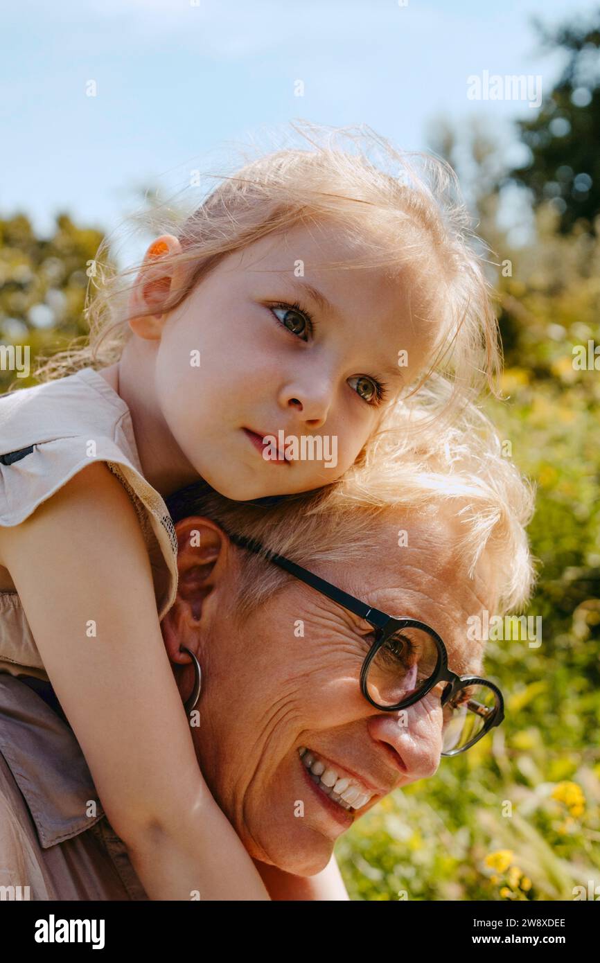 Glückliche Seniorin beim Huckepack der Enkelin im Park Stockfoto