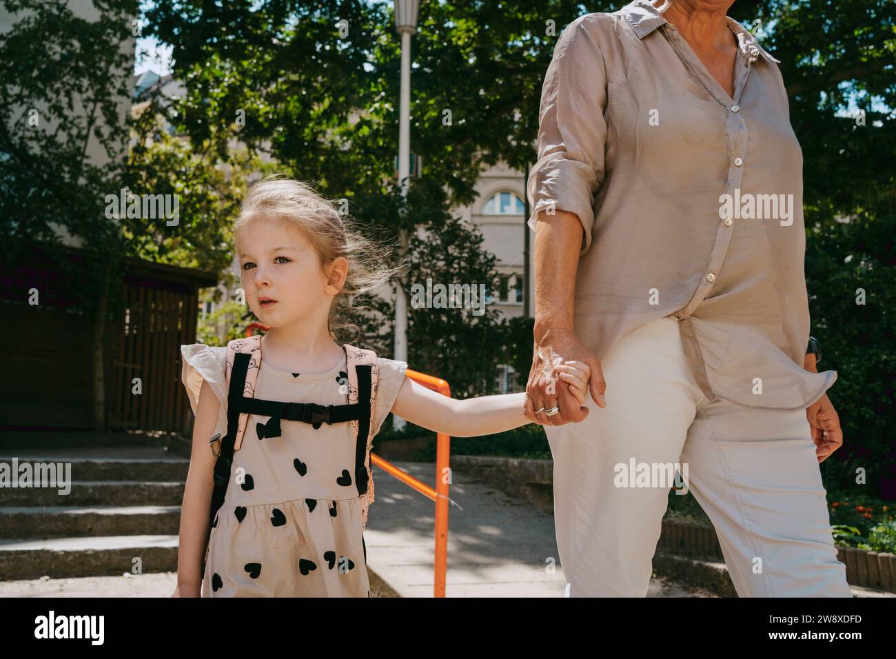 Ältere Frau, die Hände hält, während sie mit Enkelin im Kindergarten läuft Stockfoto