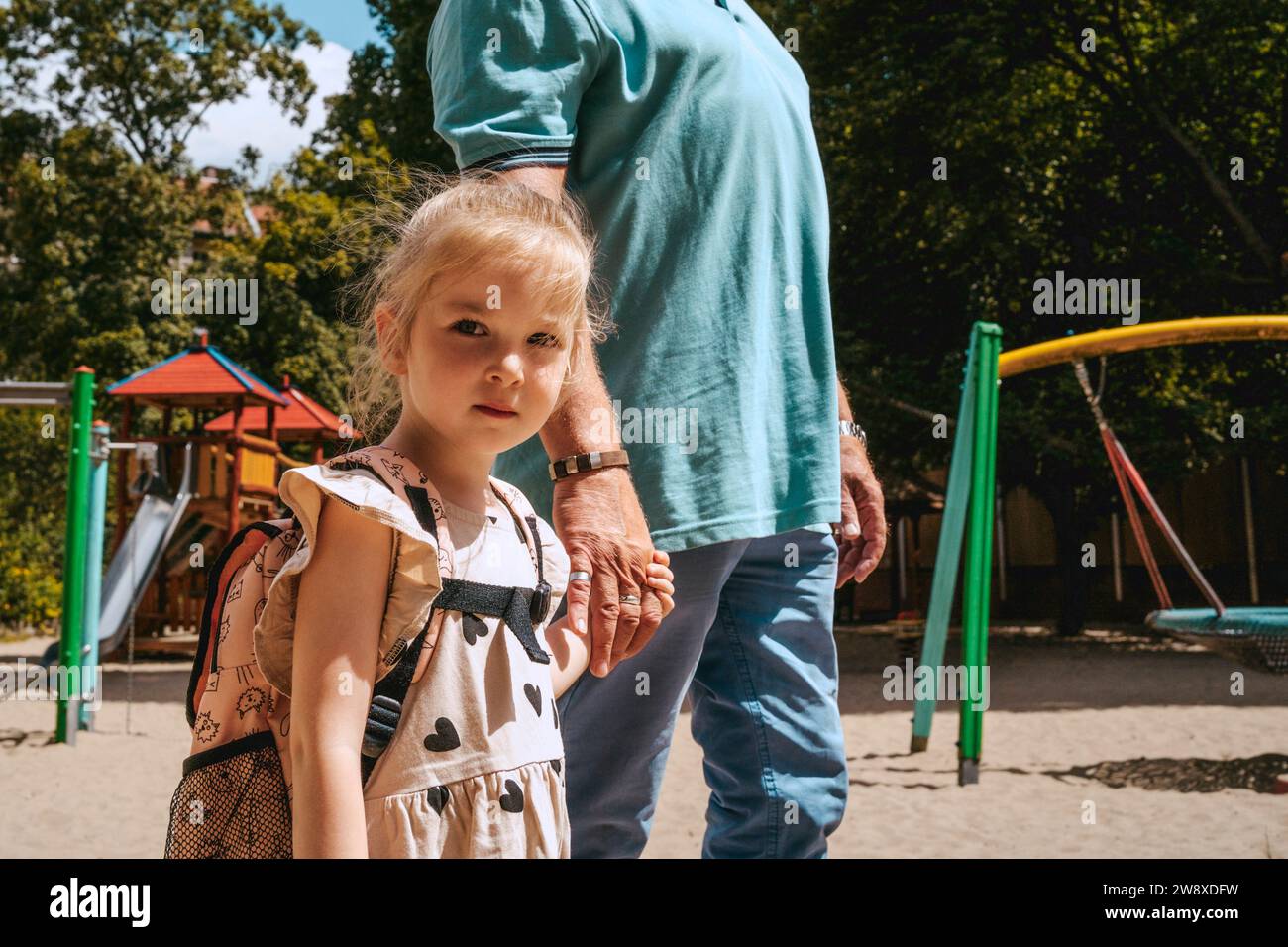 Porträt eines Mädchens, das Hände hält, während er mit Großvater im Kindergarten steht Stockfoto