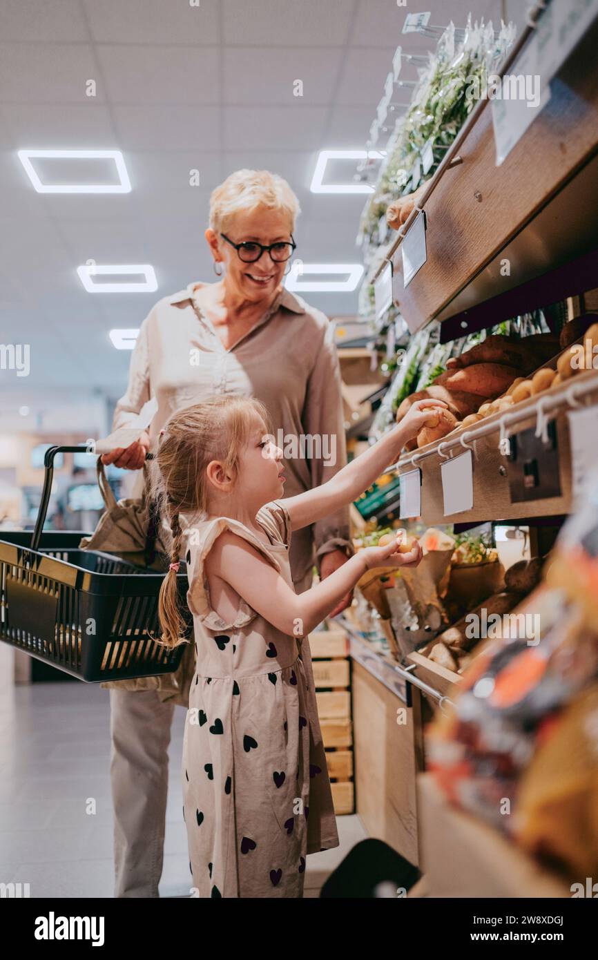 Enkelin, die mit einer Seniorin im Supermarkt einkaufen geht Stockfoto