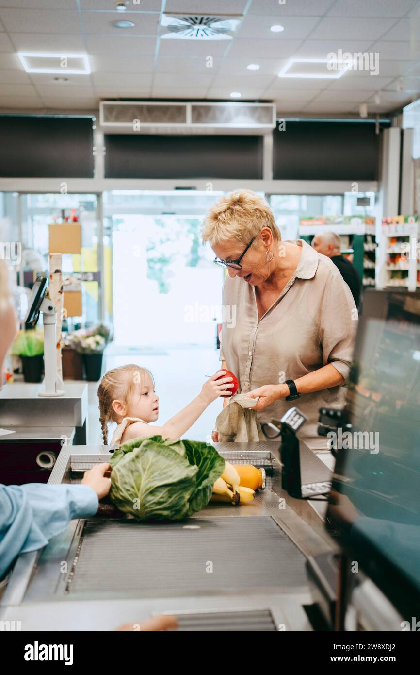 Enkelin mit Großmutter, die in der Nähe der Kasse im Supermarkt stand Stockfoto