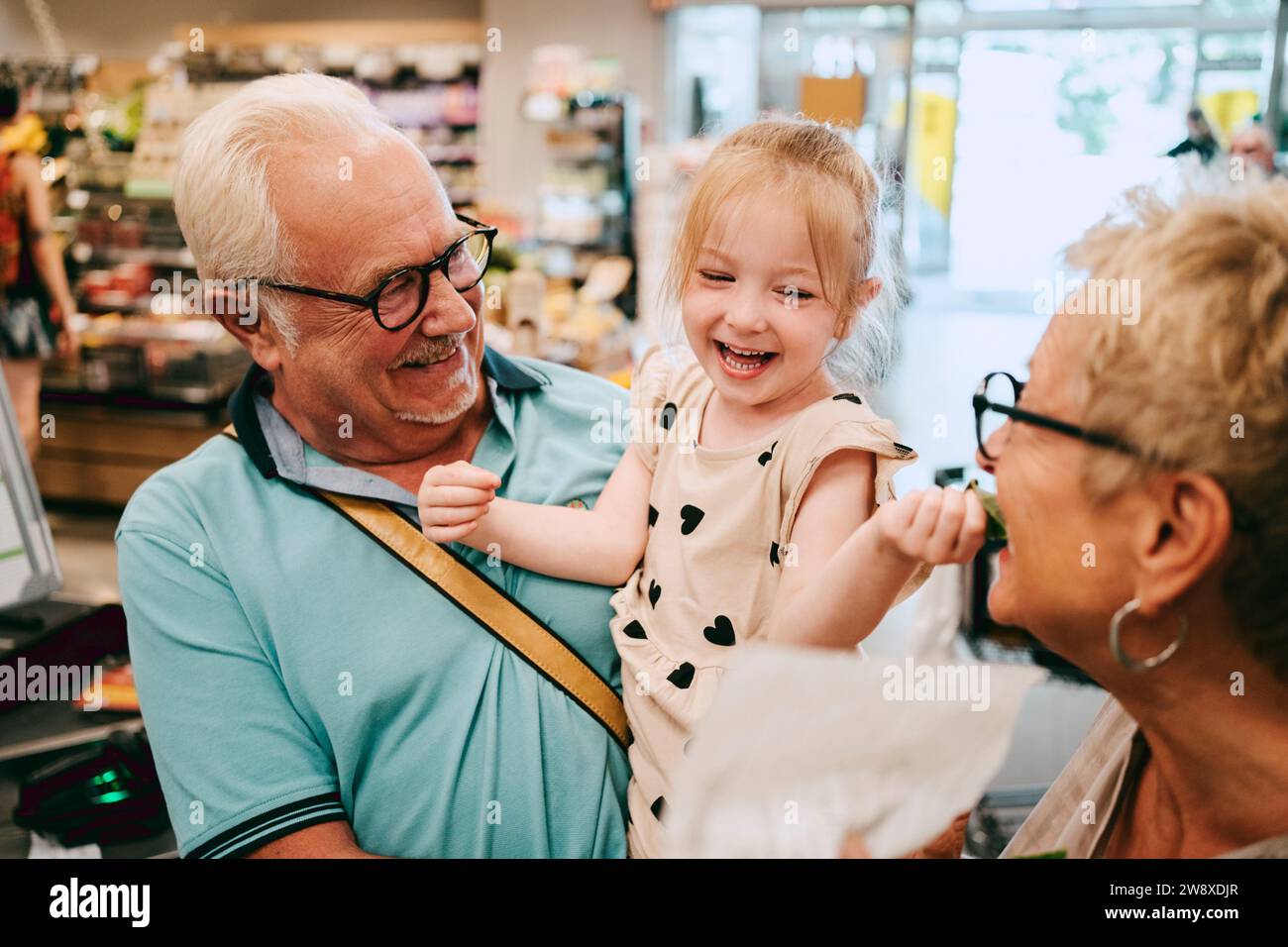 Fröhliches Mädchen, das Spaß mit Großmutter beim Einkaufen im Supermarkt hat Stockfoto