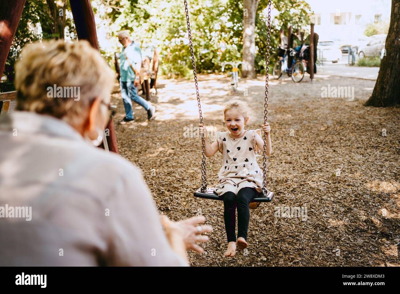 Fröhliches Mädchen, das mit Großmutter im Park auf der Schaukel spielt Stockfoto
