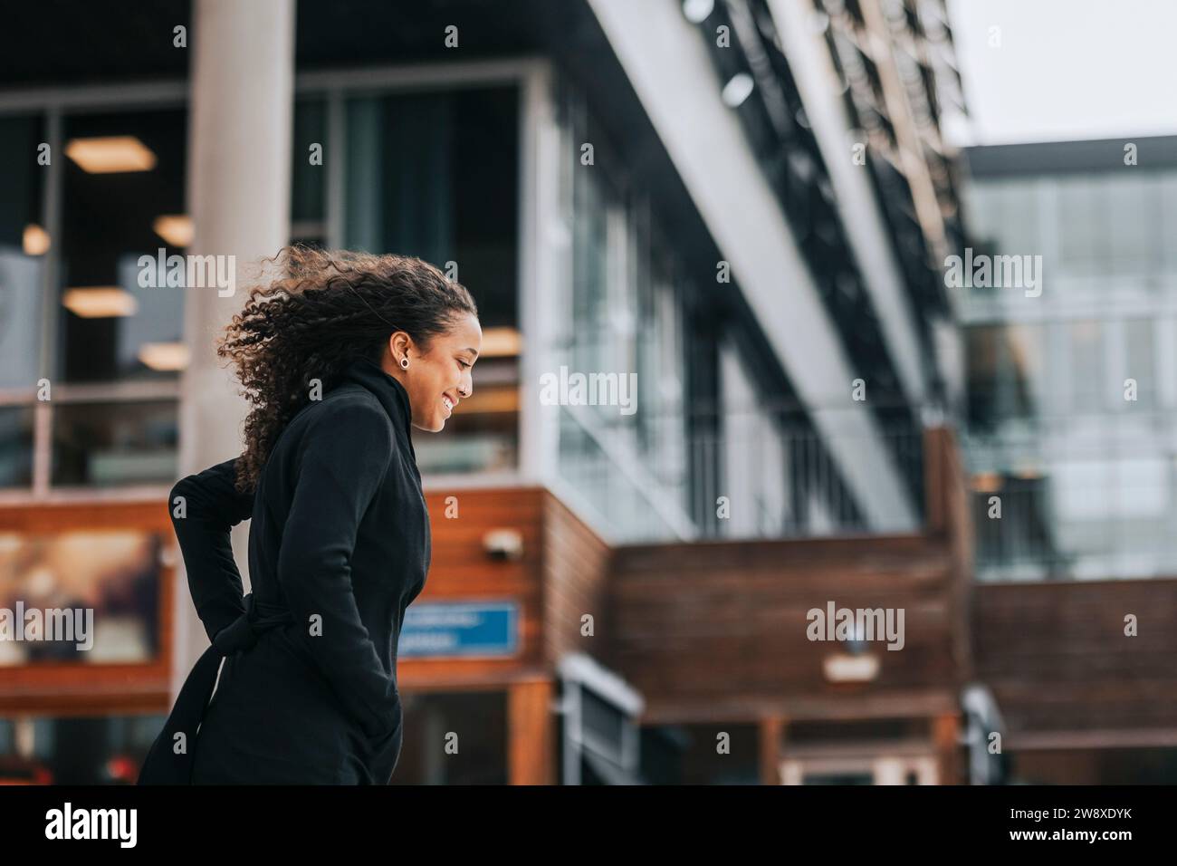 Seitenansicht einer lächelnden Geschäftsfrau, die vor dem Gebäude lief Stockfoto