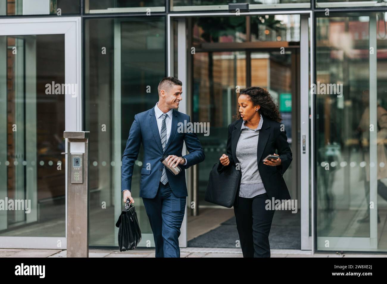 Geschäftskollegen sprechen, während sie das Bürogebäude verlassen Stockfoto