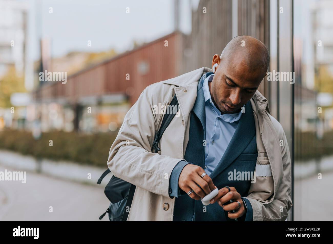 Geschäftsmann mit rasiertem Kopf und schnurlosen in-Ear-Kopfhörern Stockfoto