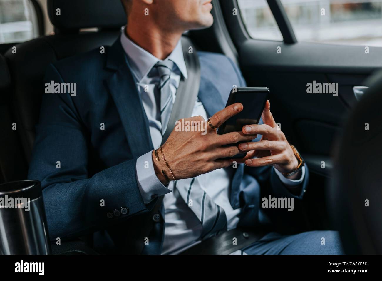 Mittelteil des Geschäftsmannes, der im Auto ein Smartphone hält Stockfoto