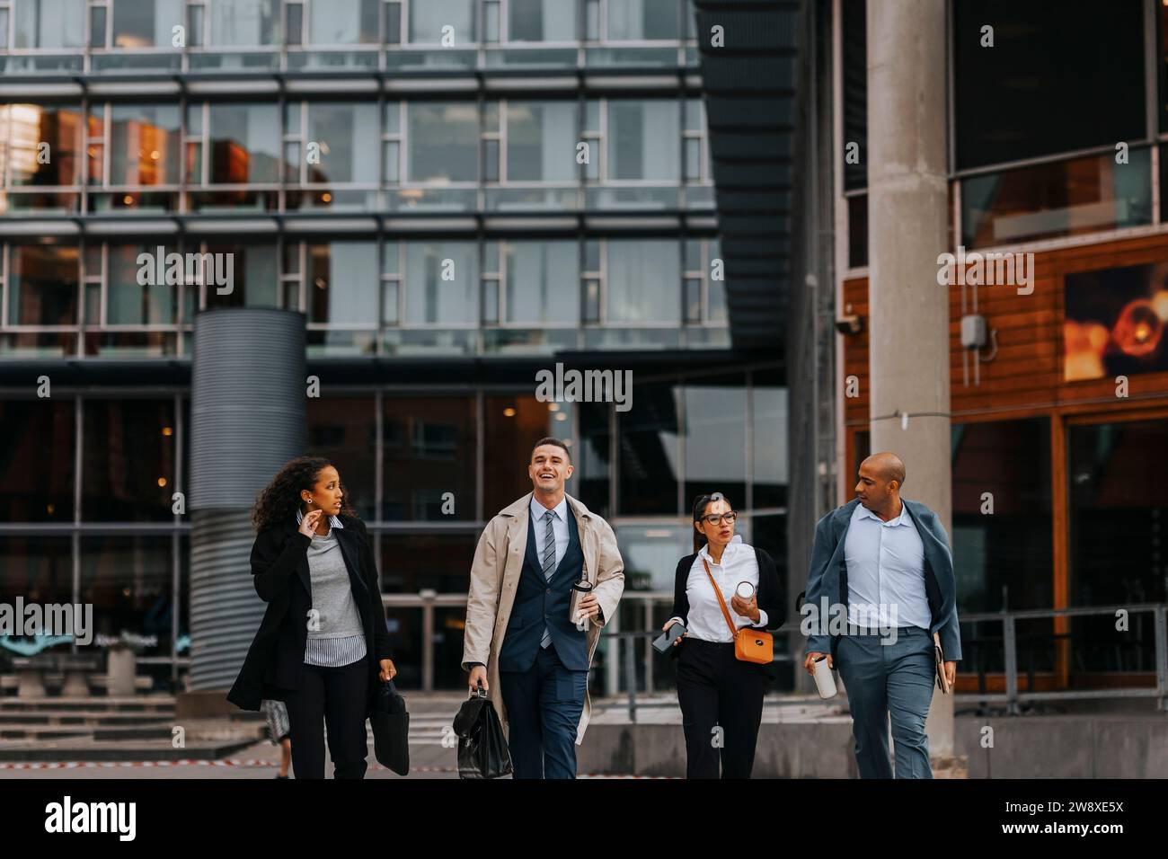 Männliche und weibliche Geschäftsleute laufen zusammen vor dem Bürogebäude Stockfoto