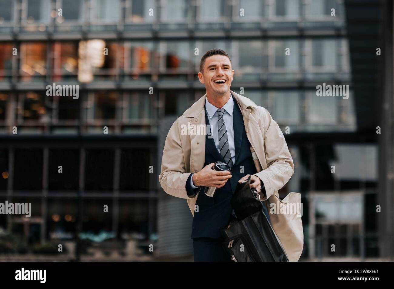 Glücklicher Geschäftsmann lacht, während er vor dem Bürogebäude läuft Stockfoto