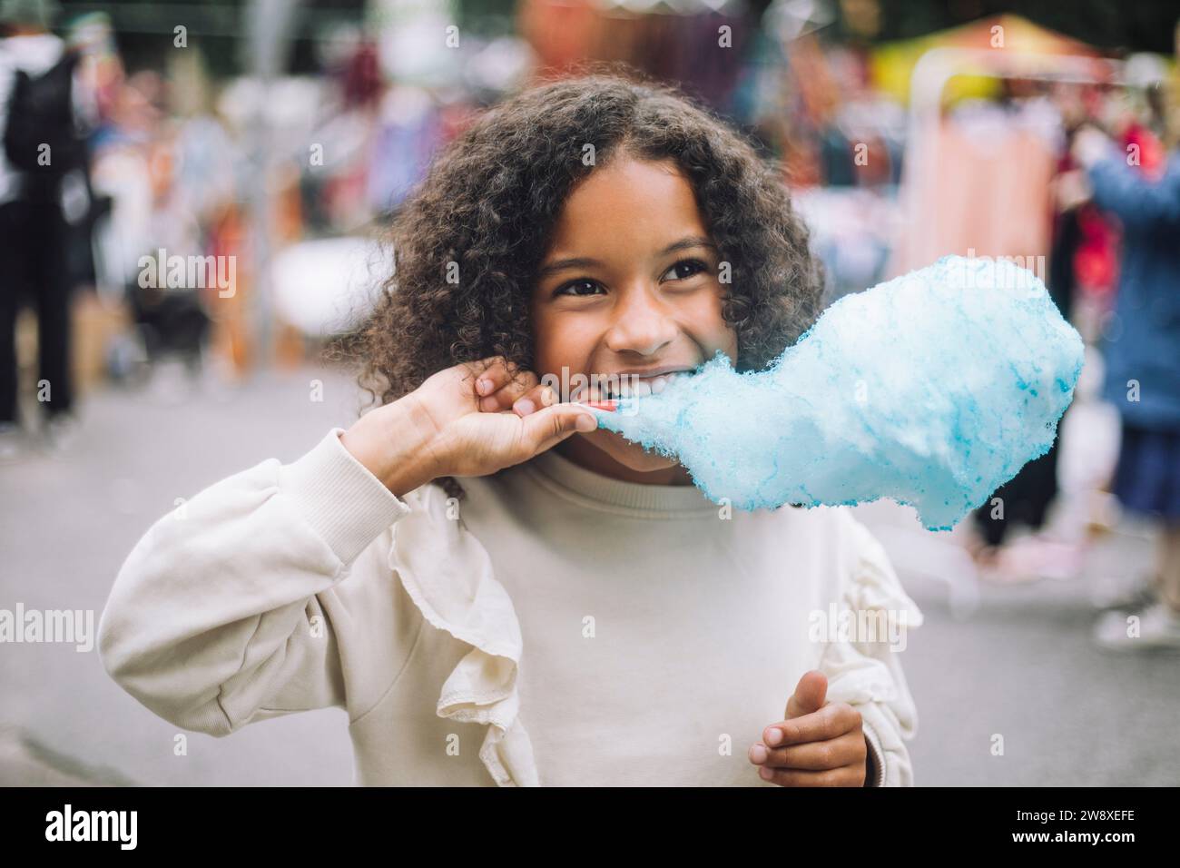 Ein nachdenkliches Mädchen isst blaue Zuckerwatte im Vergnügungspark Stockfoto