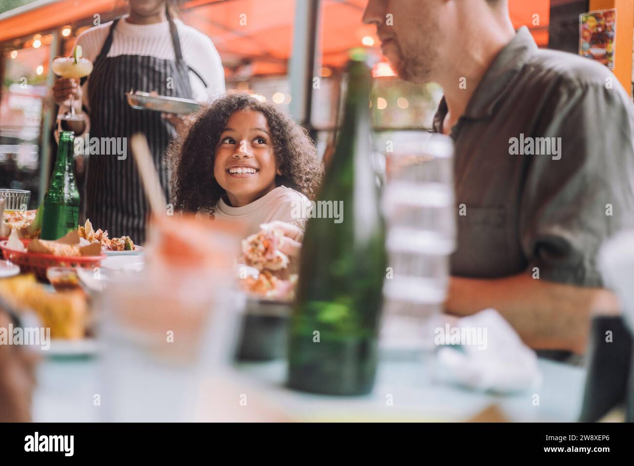 Lächelndes Mädchen beim Essen mit Vater im Restaurant Stockfoto