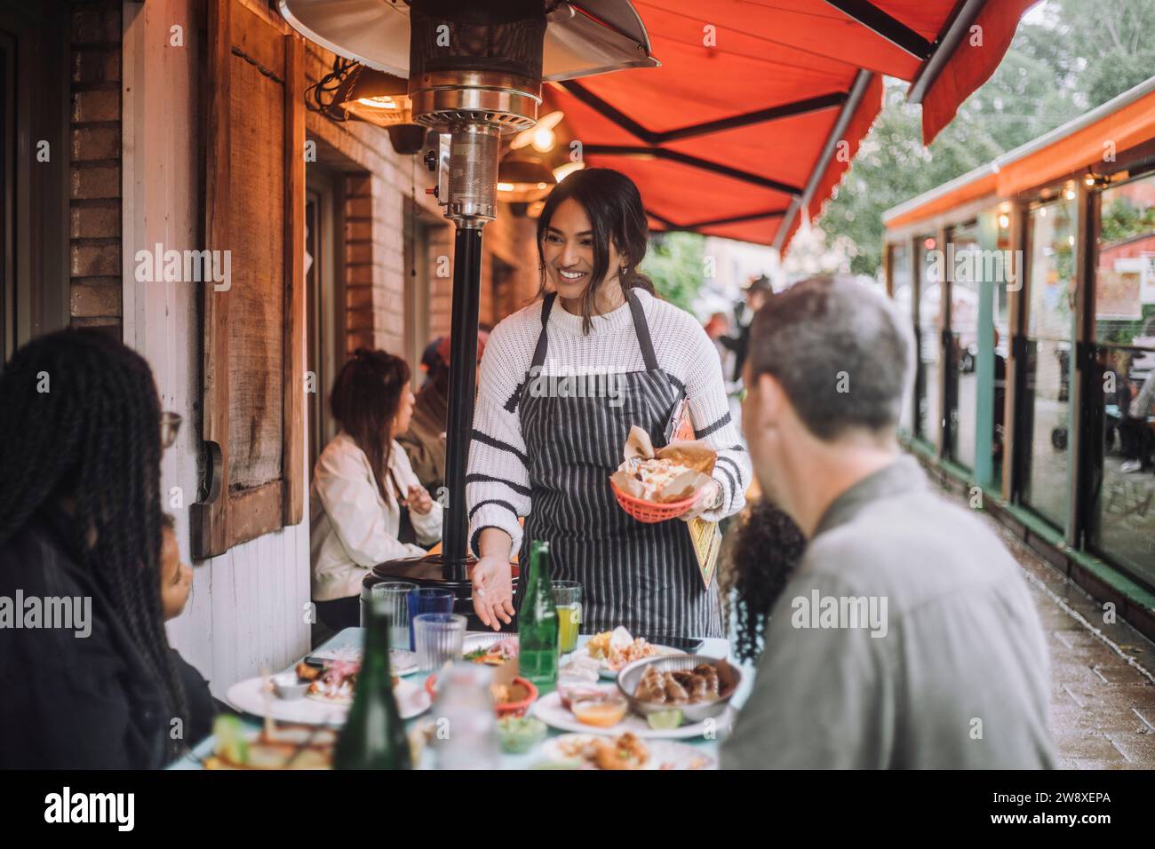 Lächelnde Kellnerin, die mit der Familie beim Essen im Restaurant spricht Stockfoto