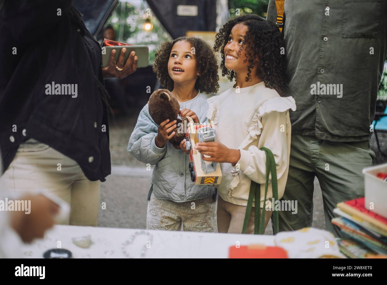 Lächelnde Geschwister, die auf dem Flohmarkt Spielzeug halten Stockfoto