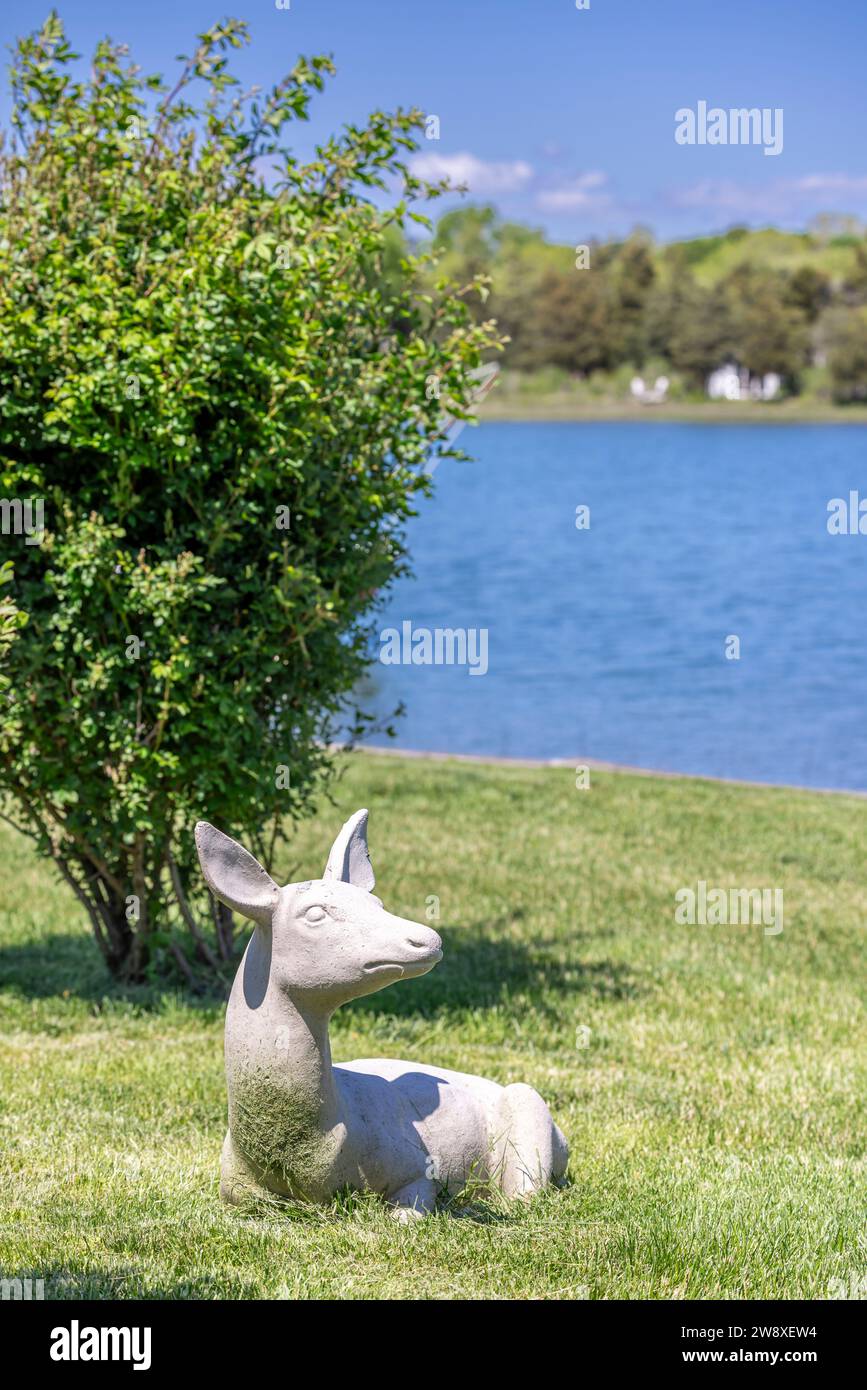 Betonskulptur einer Rehkuh, die im Gras eines Hofes liegt Stockfoto