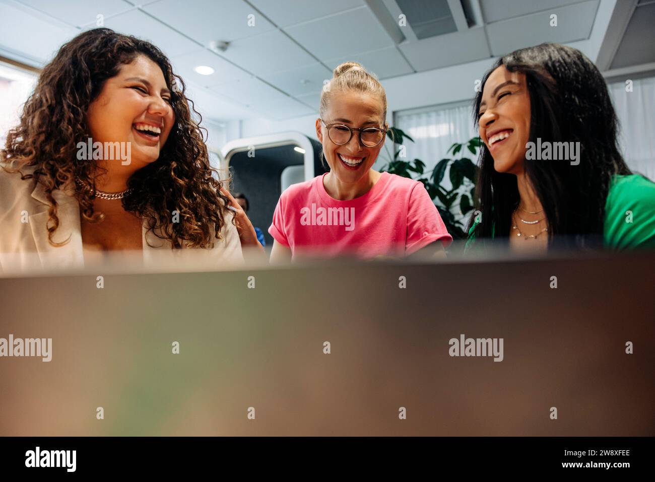 Glückliche multirassische Geschäftsfrauen, die am Arbeitsplatz lachen Stockfoto
