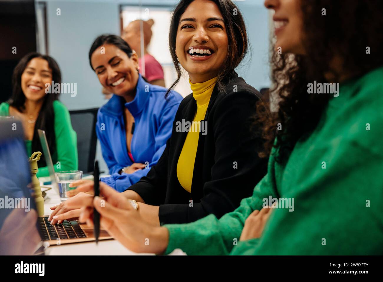 Glückliche Geschäftsfrau mit Kollegin während des Meetings am Arbeitsplatz Stockfoto