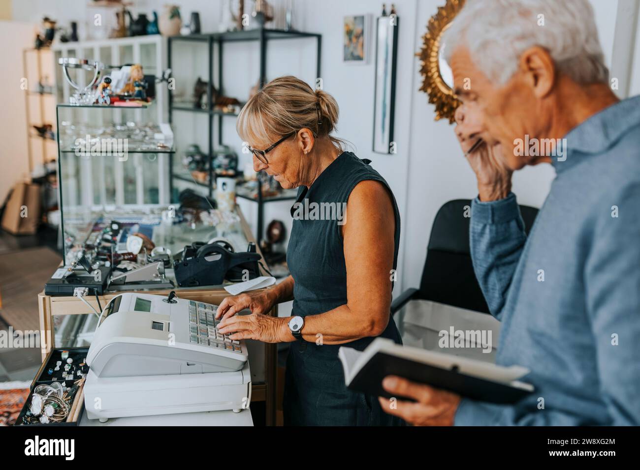 Unternehmerinnen und Unternehmerinnen stehen an der Kasse, während sie in einem Antiquitätenladen arbeiten Stockfoto
