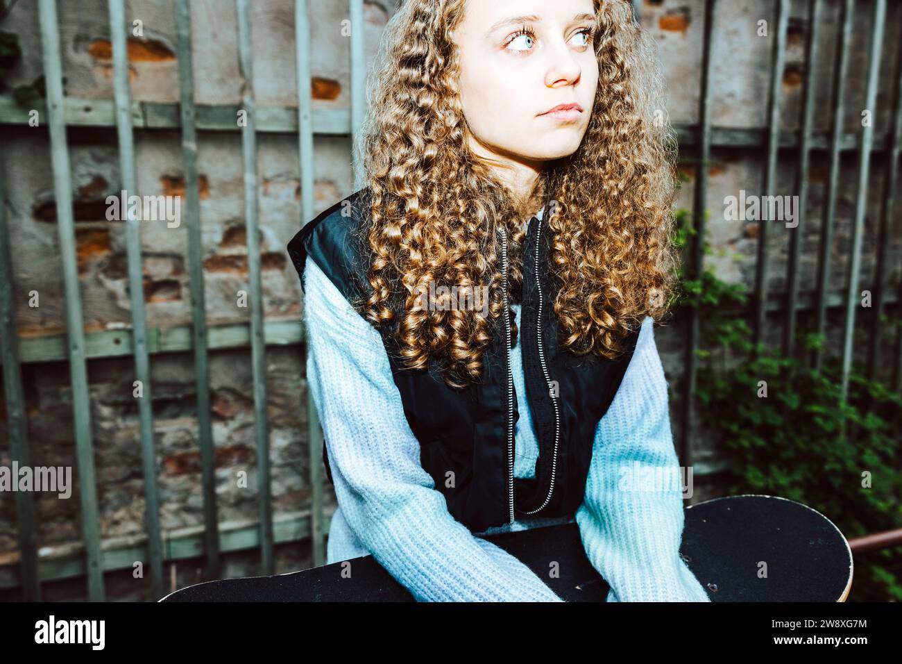 Besinnliches Mädchen mit lockigem Haar, das an die Wand schaut Stockfoto