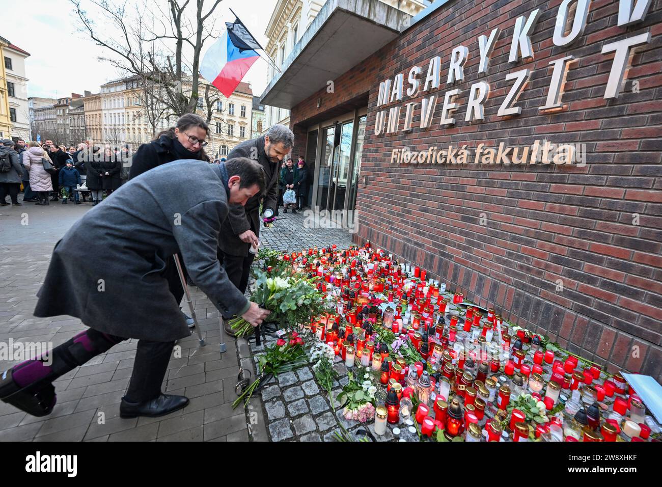 Brünn, Tschechische Republik. Dezember 2023. Ein Gotteshaus mit Kerzen, das vor der Kunstfakultät der Masaryk-Universität im Zusammenhang mit der tragischen Schießerei an der Kunstfakultät der Karlsuniversität in Prag geschaffen wurde, bei der 14 Menschen ums Leben kamen und 25 weitere verletzt wurden, in Brünn, Tschechische Republik, am 22. Dezember 2023. Hier abgebildet legt Martin Bares, Rektor der Masaryk-Universität, Blumen. Quelle: Vaclav Salek/CTK Photo/Alamy Live News Stockfoto