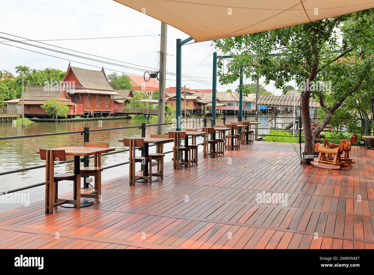 Blick auf das stilvolle hölzerne Café am Wasser im Freien mit Design für zwei Sitzplätze. Holztische und -Stühle sind einfach. Leeres Restaurant Cafe. Stockfoto