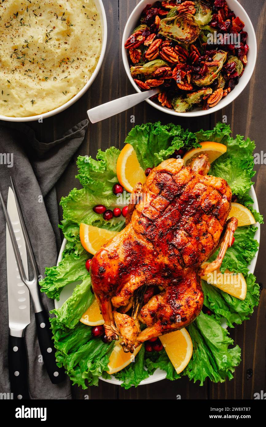 Glasierte weihnachtliche Ente mit Rosenkohl und Kartoffelpüree: Weihnachtliches Abendessen mit glasierter Ente auf einer garnierten Platte mit Beilagen Stockfoto