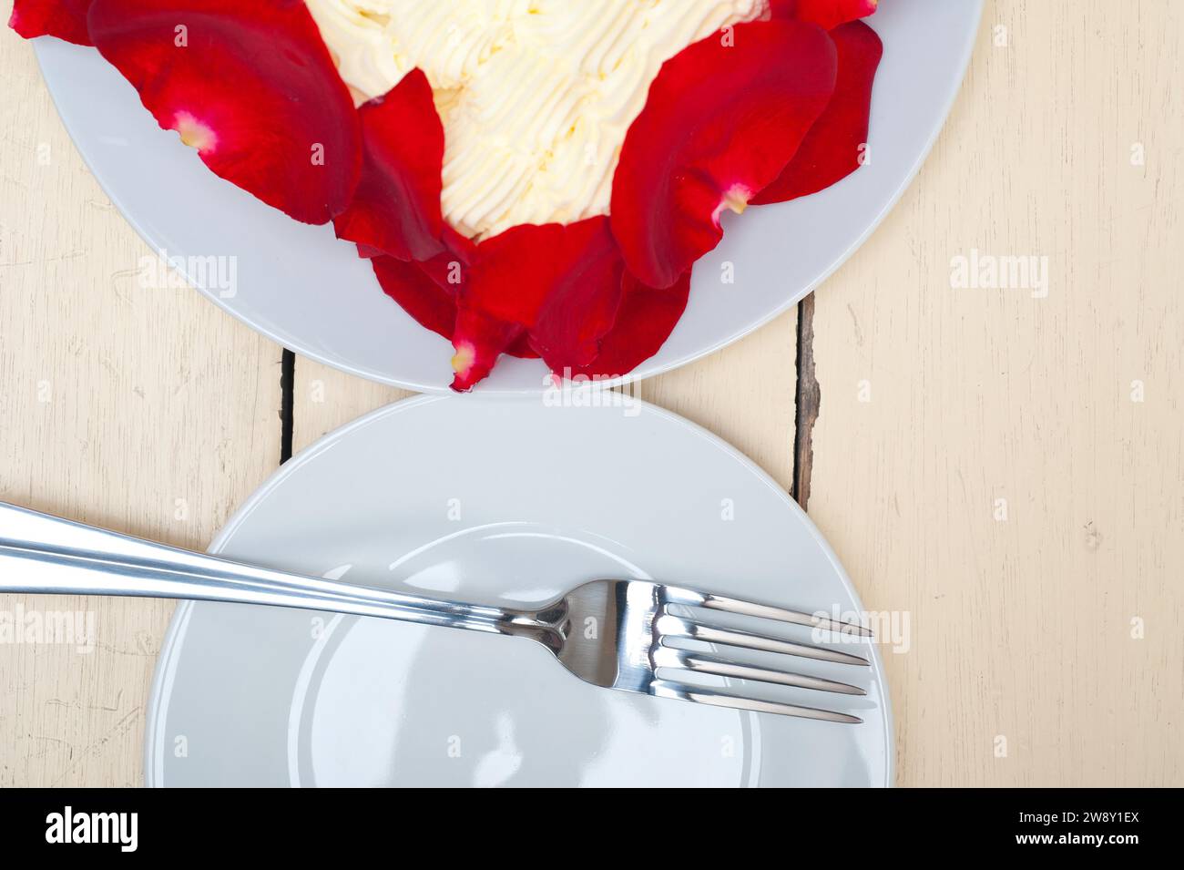 Schlagsahne-Mangobuchkuchen mit roten Rosenblättern, Lebensmittelfotografie Stockfoto