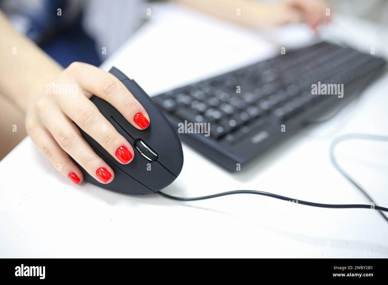 Mädchenhand verwendet einen vertikalen ergonomischen Joystick einer Computermaus. Arbeiten am Computer Stockfoto