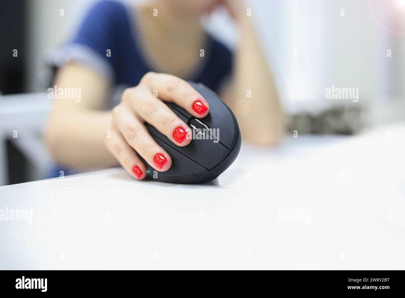 Mädchenhand verwendet einen vertikalen ergonomischen Joystick einer Computermaus. Arbeiten am Computer Stockfoto