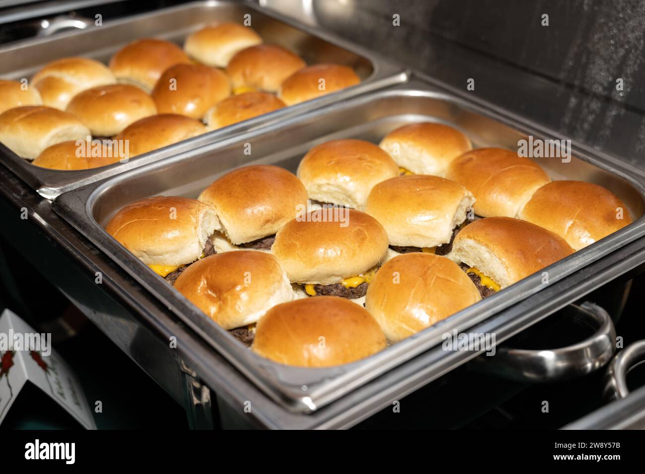 Cheeseburger-Slider mit goldgerösteten Brötchen sind in den Serviergerichten angeordnet und verzehrfertig. Stockfoto