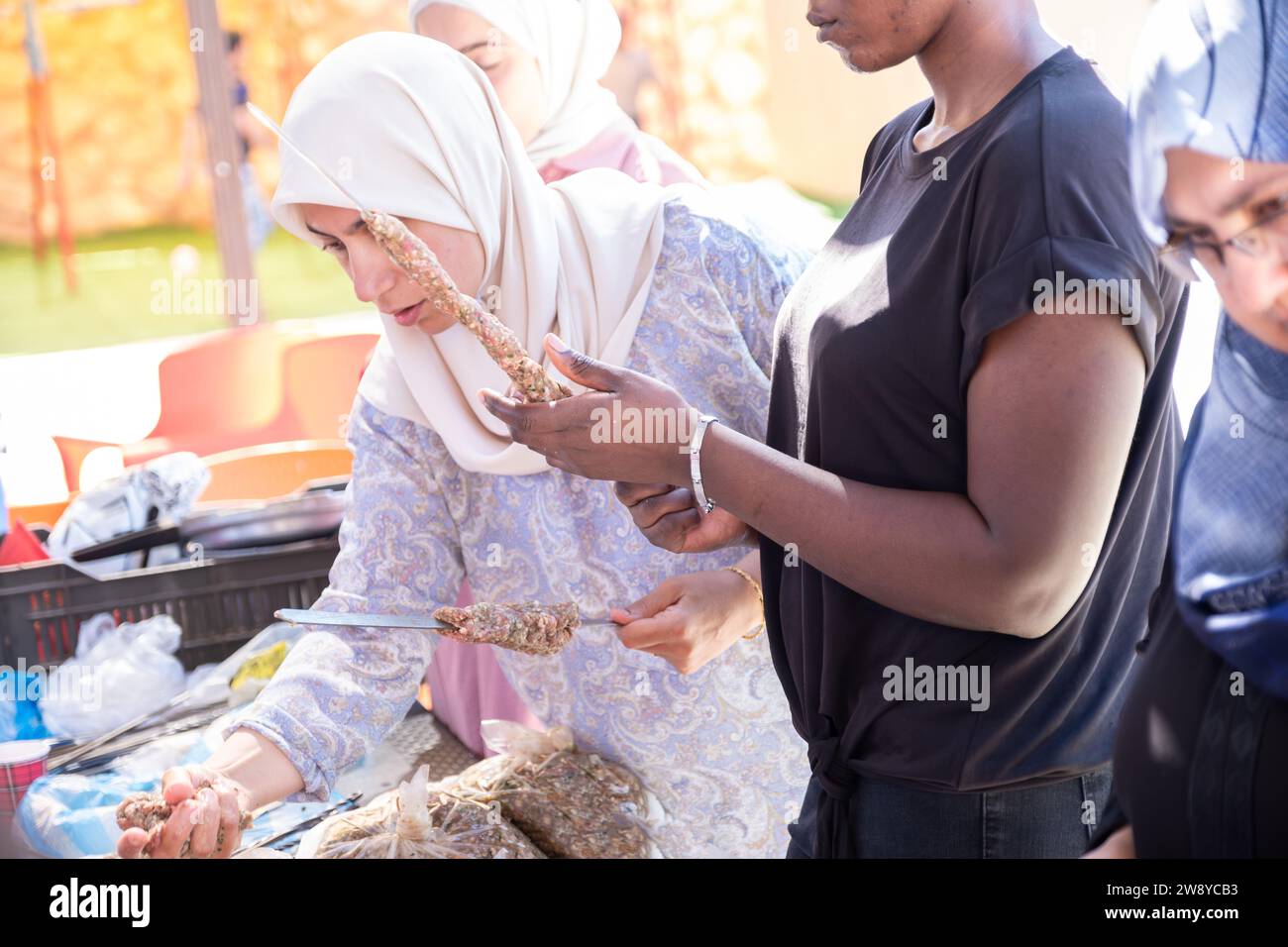 Multiethnische Völker machen ein Picknick und helfen einander bei der Zubereitung von Kebab und Barbecue Stockfoto