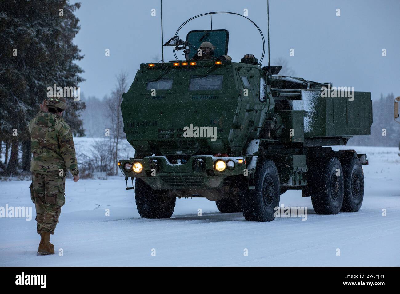 Ein Soldat der US-Armee, der der Task Force Voit, dem 3. Bataillon, dem 27. Feldartillerieregiment, der 18. Feldartilleriebrigade, dem 18. Luftlandekorps, der die 3. Infanteriedivision unterstützt. führt einen M142 Hochmobil-Artillerie-Raketensystem (HIMARS)-Trägerraketen ein, um multinationalen Truppen der NATO-Kampfgruppe Estland die HIMARS-Fähigkeiten während einer Live-Feuerübung im Central Training Area​​ in der Nähe von Camp Tapa, Estland, am 22. Dezember 2023 zu demonstrieren. Die Aufgabe der 3. Infanteriedivision in Europa besteht darin, multinationale Schulungen und Übungen auf dem gesamten Kontinent durchzuführen. Stockfoto
