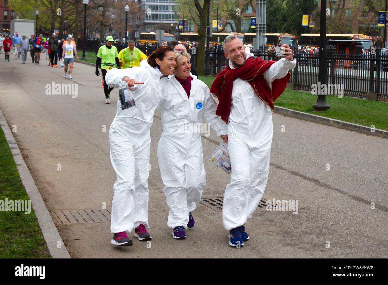 Boston, MA, USA – 17. April 2023. Drei Marathonläufer lächeln während eines Selfie in ihre Handykamera, bevor sie in den Bus steigen, um das Rennen zu starten Stockfoto