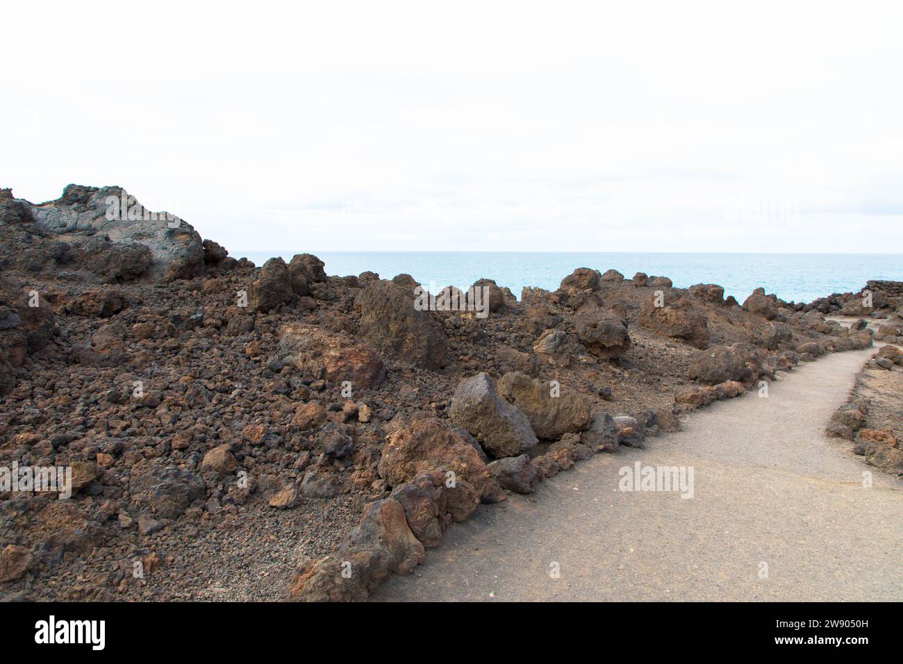 Wanderweg in Los Hervideros. Südwestküste, zerklüftete Vulkanlandschaft, Höhlen und rote Lavahügel. Lanzarote, Kanarische Inseln, Spanien Stockfoto