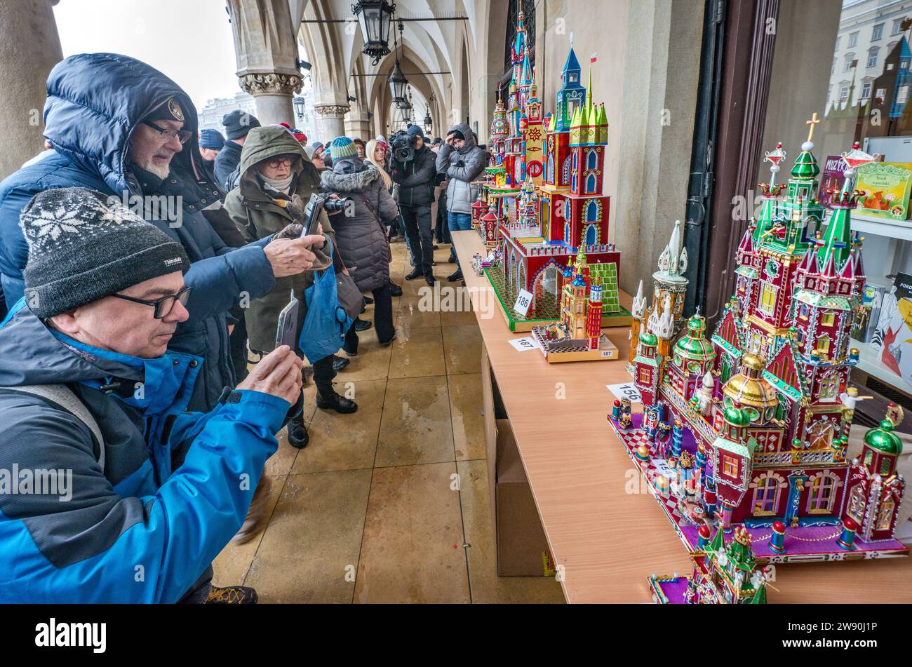 Personen, die Szopki (Weihnachtskrippen) bei der Eröffnung des jährlichen Wettbewerbs im Dezember fotografieren, Veranstaltung, die in die Liste des UNESCO-Weltkulturerbes aufgenommen wurde, in den Arkaden von Sukiennice (Tuchhalle), Hauptmarkt, Kraków, Polen Stockfoto