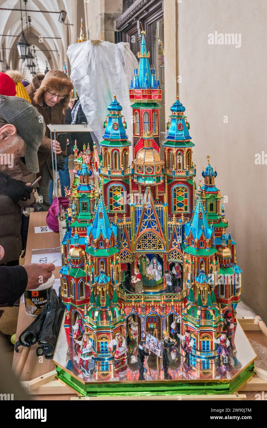 Der Künstler vervollständigt seine Szopka (Weihnachtskrippe), die bei der Eröffnung des jährlichen Wettbewerbs im Dezember in der Liste des UNESCO-Weltkulturerbes in den Arkaden von Sukiennice (Tuchhalle), dem Hauptmarkt in Kraków, Polen, gezeigt wird Stockfoto
